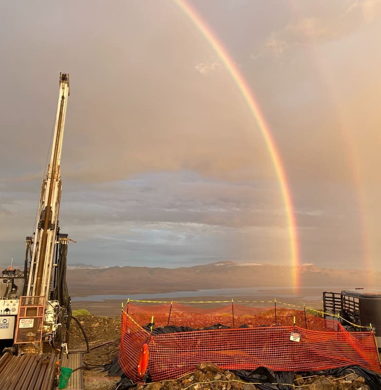 Drill rig with mast raised under a double rainbow after a passing storm