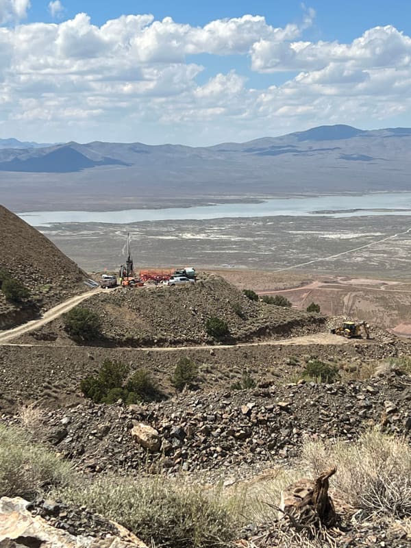 Rig on a graded ridgetop pad with the access road and basin visible below